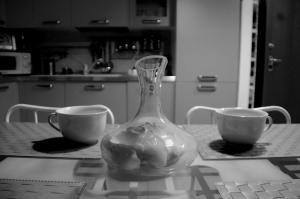 un jarrón de cristal sentado en una mesa junto a dos tazas en Elly House en Casalecchio di Reno