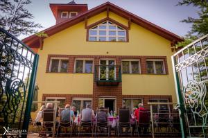 un grupo de personas sentadas en una mesa frente a una casa en Sába-Ház, en Balatonboglár