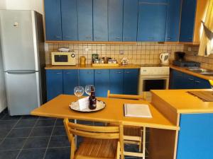 a kitchen with blue cabinets and a table with a wine glass at Semi's House in Batsi +35 photos
