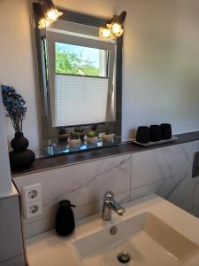 a bathroom sink with a mirror and a window at Gute Stube in Hohen Neuendorf +8 photos