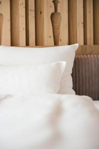 a close up of a bed with white pillows at Boutique Hotel Pachers in Bressanone