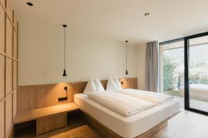 a bedroom with a large white bed and a window at Boutique Hotel Pachers in Bressanone