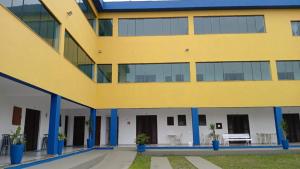 Een exterieurbeeld van een geel gebouw met blauwe zuilen. bij Pousada Beira Mar in Mongaguá