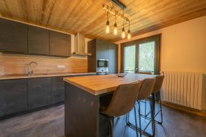 a kitchen with a wooden ceiling and a island with bar stools at Etoile des Vents 1 in Morzine +4 photos