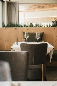 two wine glasses sitting on a table in a restaurant at Boutique Hotel Pachers in Bressanone