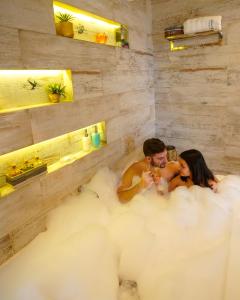 a man and a woman sitting in a bathtub engulfed in a cloud at Cabañas Chic Cumbre in Sierra de los Padres