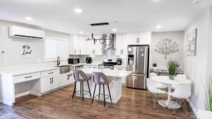 a kitchen with white cabinets and a table and stools at Xlnc Exotic Home Gillespie Drive in Spring Valley