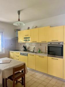 a kitchen with yellow cabinets and a table in it at Apartments Ballabanka in Koper