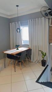 a dining room with a table and chairs and a window at Apart 3qtrs á 1200m da praia de Itapuã in Vila Velha