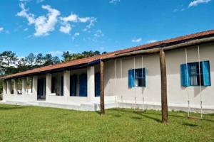 a white building with blue windows and a grass field at Casa Acuri in Jacareí