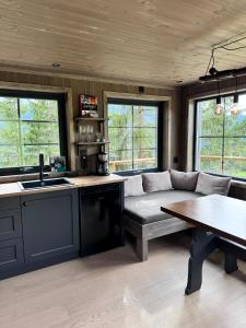 a kitchen and living room with a couch and a table at Fjellgla tretopphytte in Holo