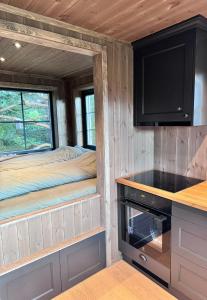 a tiny house with a bunk bed and a kitchen at Fjellgla tretopphytte in Holo