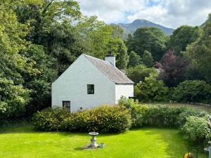 a white house in the middle of a yard at The Bothy of Ballachulish House in Ballachulish