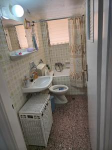 a bathroom with a sink and a toilet and a window at loutraki apartment in Loutraki