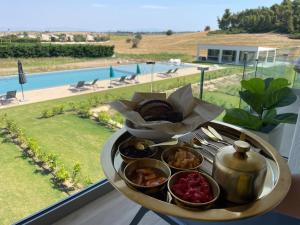 a tray of food on a table in front of a window at Oikos Sani Suites in Sani Beach