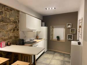 a kitchen with white cabinets and a stone wall at Ferme de Filot in Filot