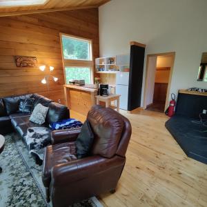 a living room with a leather couch and a kitchen at Hummingbird B&B in Gabriola +36 photos