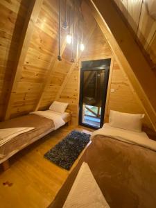 deux lits dans une chambre aux murs en bois dans l'établissement Vila Hedonija, à Žabljak