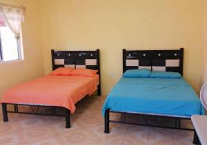 twee bedden naast elkaar in een kamer bij Villa del Sol in Barra de Potosi