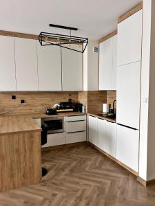 a kitchen with white cabinets and wooden floors at Apartamenty Termal Water Długa 31 in Uniejow +5 photos