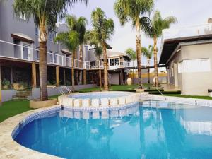 a swimming pool in front of a building with palm trees at Enjoy 360 in Villa Carlos Paz