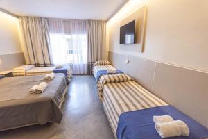 a hotel room with three beds and a tv at Enjoy 360 in Villa Carlos Paz