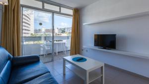 a living room with a couch and a tv and a table at Tagoror Beach Apartments - Adults Only in Playa del Ingles