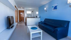 a living room with a blue couch and a table at Tagoror Beach Apartments - Adults Only in Playa del Ingles