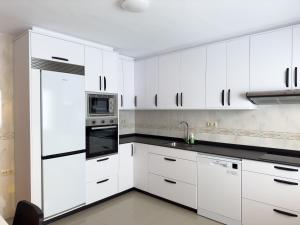 a white kitchen with white cabinets and appliances at O Nido de Noe in Melide