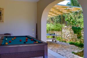 Una mesa de billar en un patio trasero con un arco. en Villa Mylos, en Kassiopi