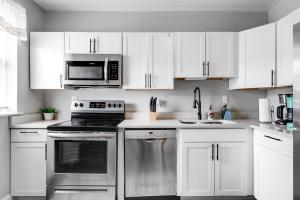 una cucina con armadietti bianchi ed elettrodomestici in acciaio inossidabile di Cozy spacious family home near Carytown fully fenced a Richmond