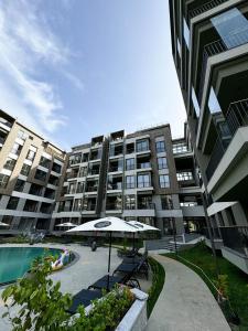 a large apartment building with an umbrella and a pool at Realest Property Groups, Diamond in The City in Accra