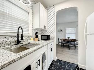 a white kitchen with a sink and a microwave at Budget-friendly 1br Prime Orlando Location in Orlando