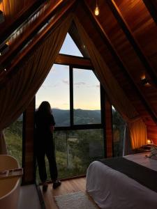a person standing in a room with a large window at Cabana The Wild Urubici in Urubici