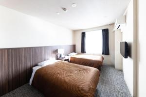 Una habitación de hotel con dos camas y un televisor. en Reco Hotel Mikuni, en Toyonaka