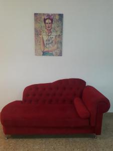 a red couch in a room with a picture on the wall at FRIDA APARTMENT remis gratis a Ezeiza in Ezeiza +1 photo
