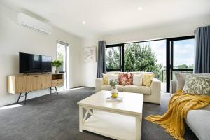 a living room with a couch and a tv at Riverview Retreat-4 bedrooms Brand New House In Hamilton in Hamilton