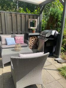 a patio with a grill and wicker chairs and a barbecue at De groene oase de Boschberg in Biddinghuizen