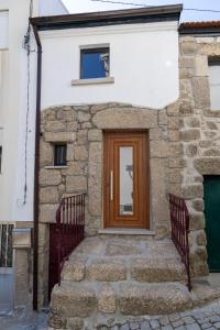 a stone house with a wooden door and stairs at Casa da Carqueija in Valezim