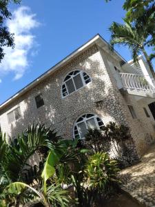 a large stone building with white windows and palm trees at Ella villa negril in Negril