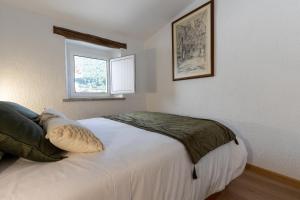 a bedroom with a large white bed with a window at Casa da Carqueija in Valezim