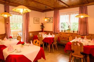a restaurant with tables and chairs with red table cloth at Pension Talblick in Laion