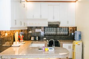 a kitchen with white cabinets and a sink at Caliah Homes in Balamban