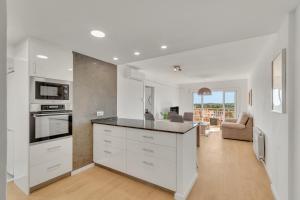 a kitchen with white cabinets and a living room at Sea View Penthouse in Vilanova i la Geltrú