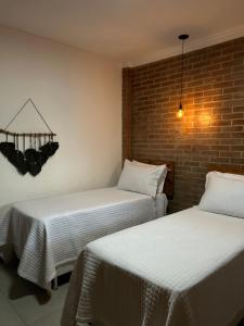 two beds sitting next to a brick wall at Pousada Bem Viver in Nobres