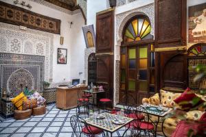a restaurant with tables and chairs in a room at Riad LalaMoune in Fez