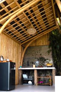 a kitchen with a black refrigerator and a wooden ceiling at Danaswari Bali Bamboo House in Selat +65 photos