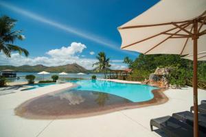 a swimming pool with an umbrella and the ocean at EL RIO Y MAR RESORT in Coron