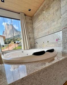 a bath tub in a bathroom with a large window at Pousada Refúgio Pietra Blu in Domingos Martins +36 photos