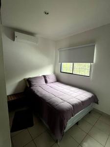 a bed in a small room with a window at Oasis Urbano en Managua in Managua